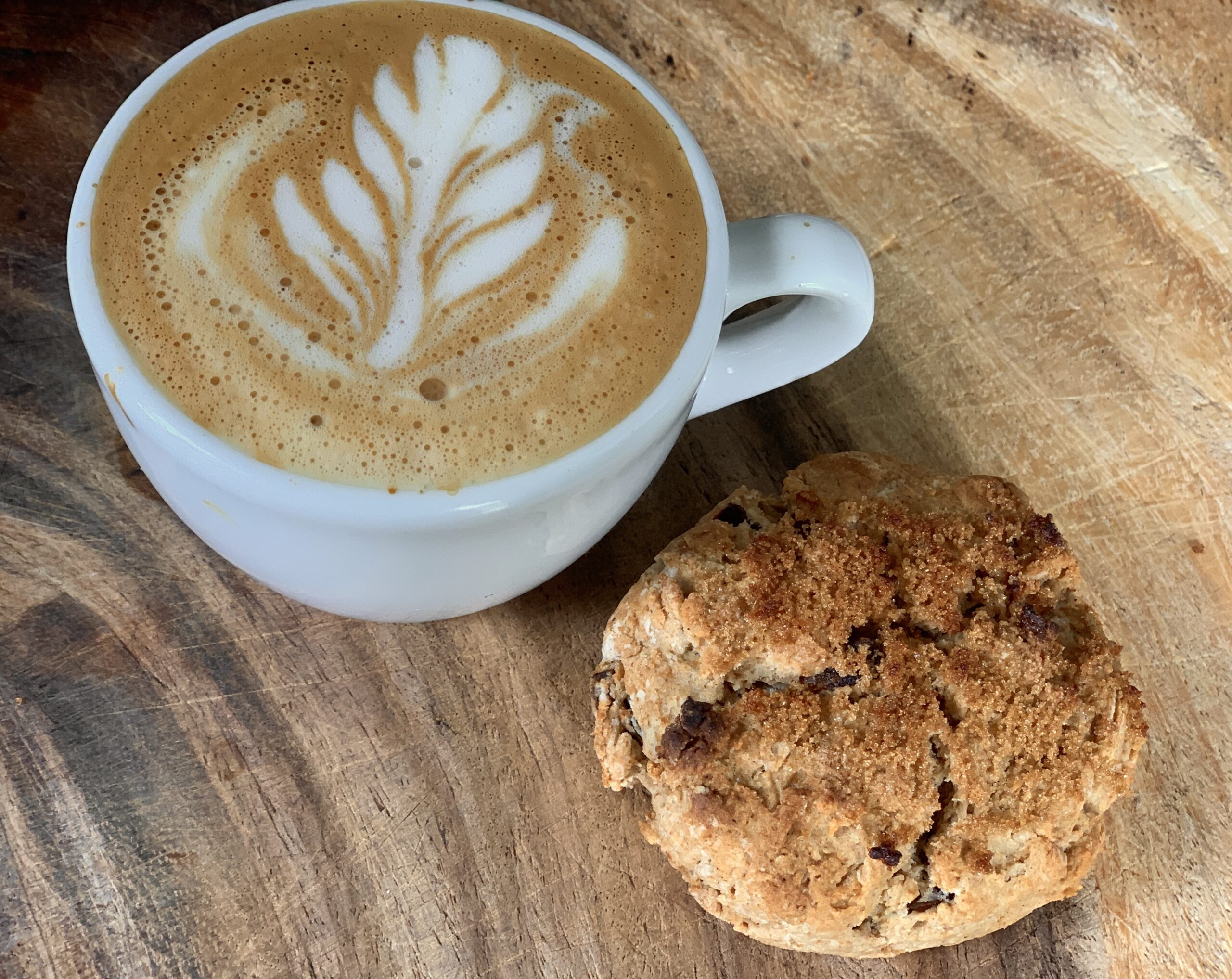 Photo of a fresh home-made flat white coffee and date scone.